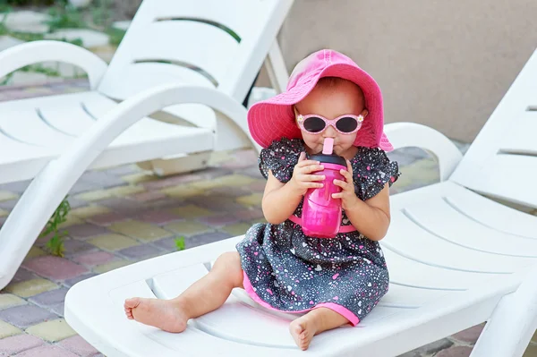 Pequena menina no parque de outono bebidas de garrafa de plástico rosa — Fotografia de Stock