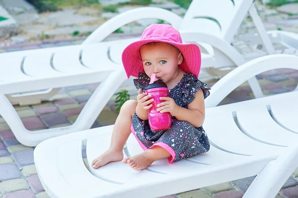 Kleines Mädchen im Herbst Park trinkt aus rosa Plastikflasche — Stockfoto