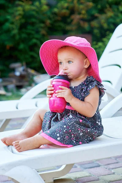 Pequena menina no parque de outono bebidas de garrafa de plástico rosa — Fotografia de Stock