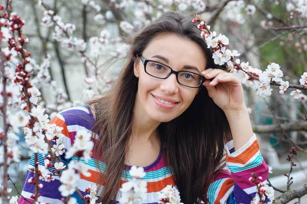 Портрет улыбающейся кавказской брюнетки женщины в весеннем цветущем саду — стоковое фото