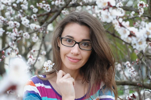 Portret van lachende Kaukasische brunette vrouw in bloesem lentetuin — Stockfoto