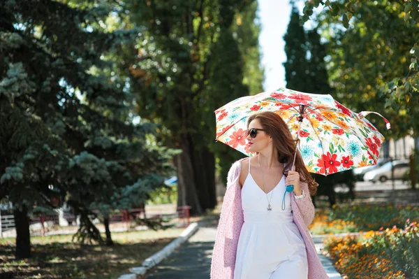 Belle femme en lunettes de soleil avec parasol marchant dans le parc — Photo