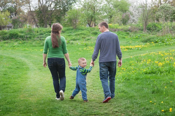 Les parents marchent avec un petit garçon sur un pré vert de printemps sur un sentier — Photo