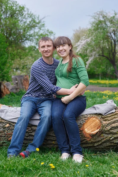 Marido y su esposa embarazada sentados en una cubierta de madera — Foto de Stock