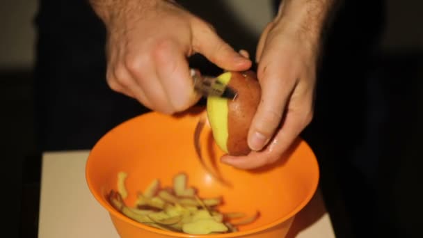 Man skalar potatis i köket för förbereda mat — Stockvideo