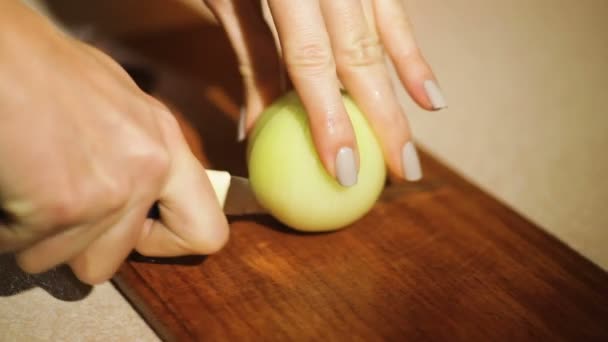Vrouw snijdt UI in de keukenmes op een snijplank — Stockvideo
