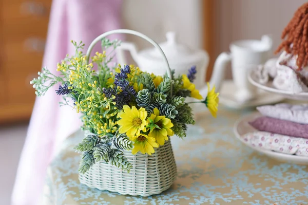 Bouquet de fleurs jaunes dans un panier en osier blanc debout sur une table en bois — Photo