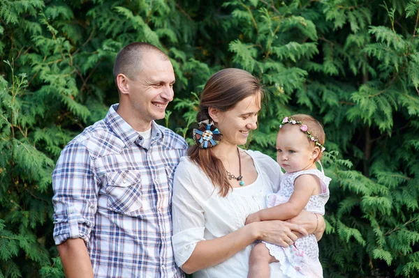 Yeşil yaprakları olan bir arka plan üzerinde küçük bir kızı mutlu aile — Stok fotoğraf