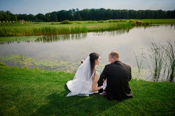 Novio y la novia caminan cerca del lago el día de su boda —  Fotos de Stock