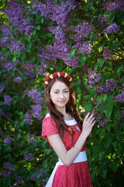 Mulher jovem com grinalda e com flores lilás na primavera — Fotografia de Stock