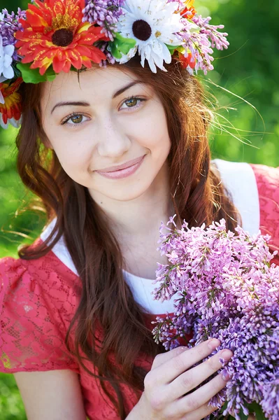 Ung kvinna med krans och med lila blommor på våren — Stockfoto