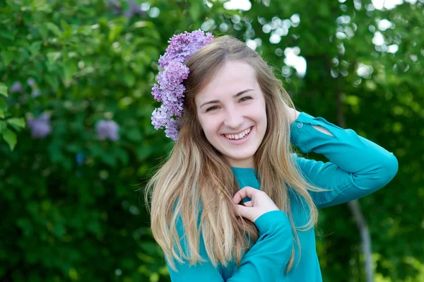 Portret van een mooie jonge vrouw met een krans in voorjaar park — Stockfoto