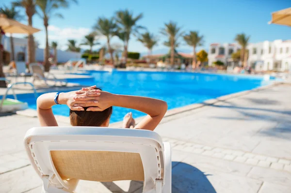 Frau liegt auf einer Liege und schaut in den Pool — Stockfoto