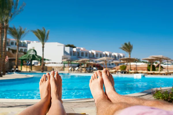 Male and female legs on the background of the pool at the hotel — Stock Photo, Image