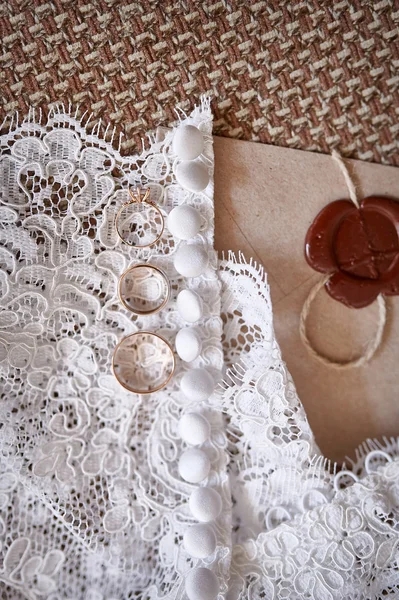 Vigselringar från gult guld ligga på en klänning bruden — Stockfoto