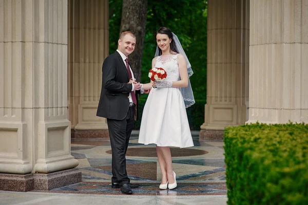 Bride and groom with a bouquet of walking in the summer park — Stock Photo, Image