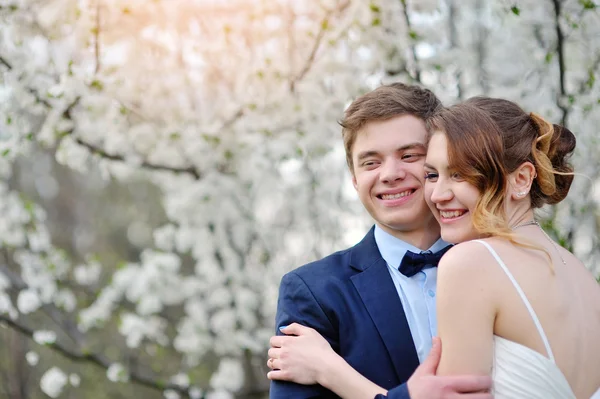 Happy bride and groom in a blossoming spring garden — Stock Photo, Image