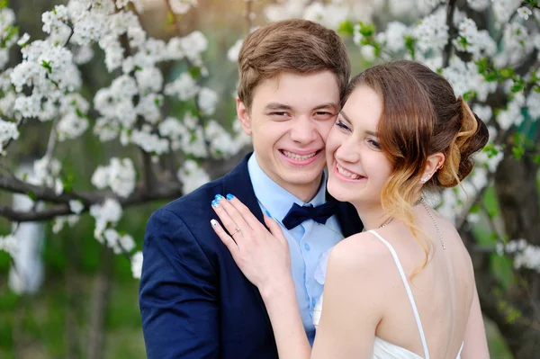 Lyckliga bruden och brudgummen i en blommande vår trädgård — Stockfoto