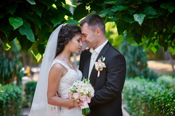 Novia y novio con un ramo de caminar en el parque de verano — Foto de Stock