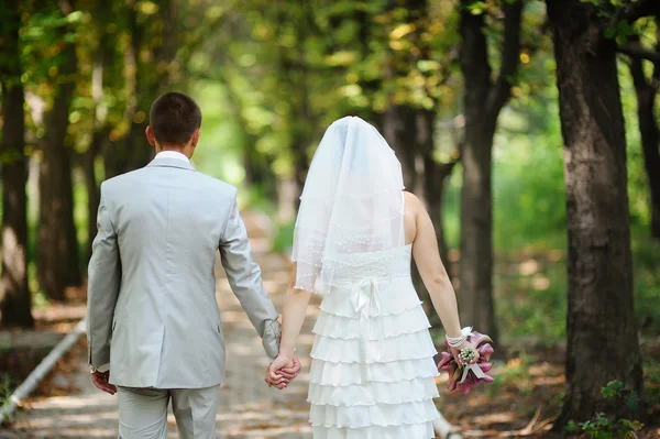 Bride and groom walking away in summer park outdoors — Stock Photo, Image