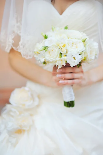 背景に白いドレスと花嫁の手の中結婚式の花の花束 — ストック写真