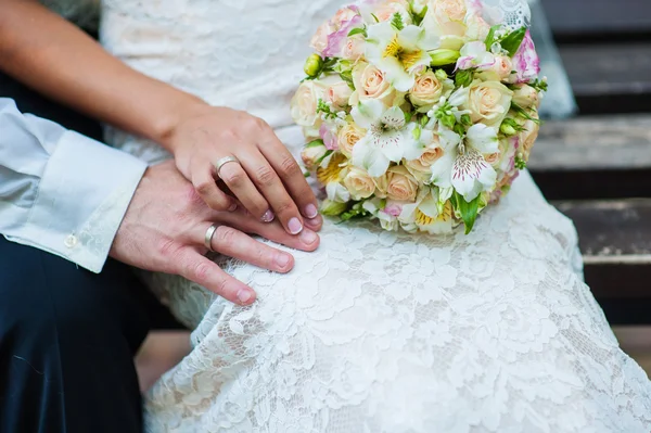 Handen van bruid en bruidegom met ringen op bruiloft boeket — Stockfoto