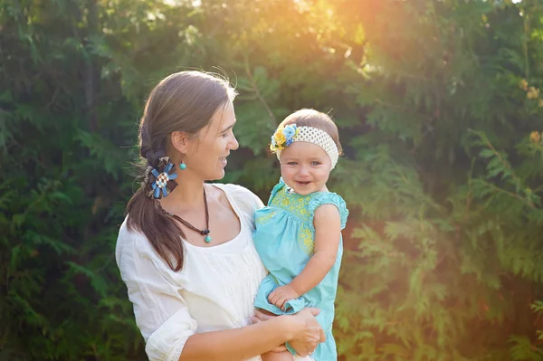 Mamá mantiene a su hija en sus brazos y juega con la naturaleza —  Fotos de Stock