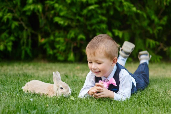 Kleine jongen spelen met een konijn op het gras in het park — Stockfoto