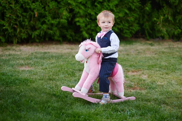 Bébé garçon jouer avec cheval sur aire de jeux dans le parc — Photo