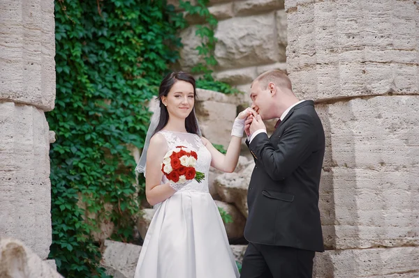 Marié embrassant sa mariée le jour du mariage près de l'arche — Photo
