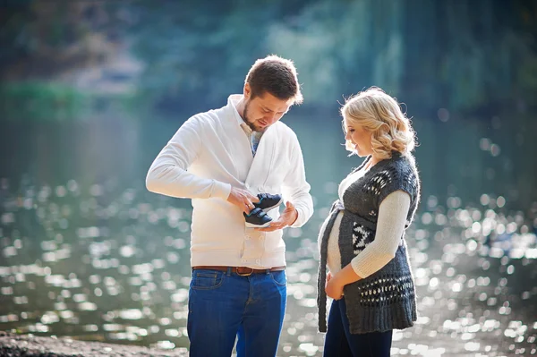 Szczęśliwe kobiety w ciąży i jej mąż podczas spaceru z człowiekiem, w pobliżu jeziora — Zdjęcie stockowe