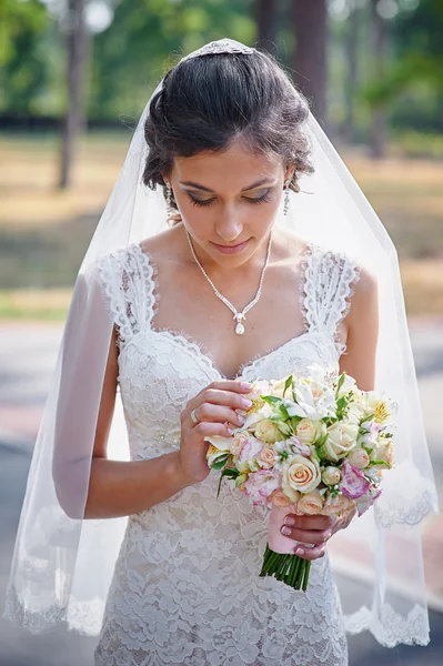 Nevěsta v bílém oblečení v létě zelený park s kyticí v ruce — Stock fotografie