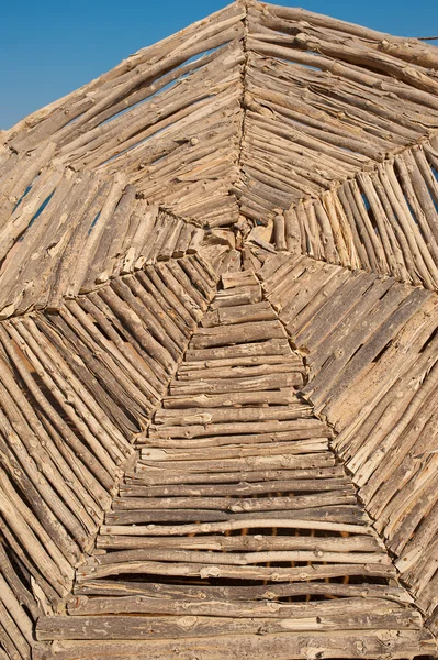 Big wicker wooden parasol against blue sky on beach — Stock Photo, Image