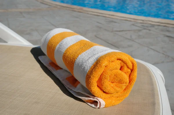 Yellow towel lying on a lounger beside the swimming pool — Stock Photo, Image