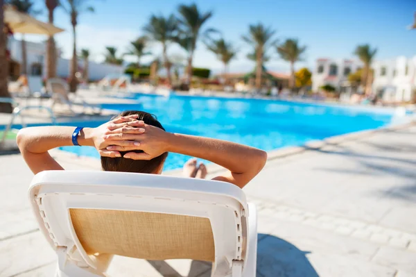 Glückliche Frau auf einer Liege am Pool des Hotels liegend — Stockfoto