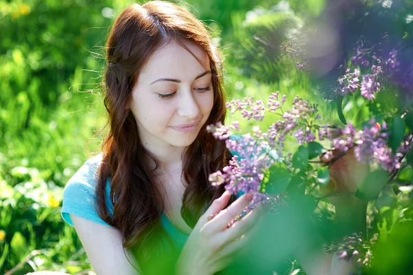 Schöne Frau neben dem Flieder im Park — Stockfoto