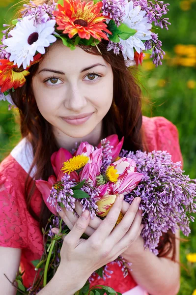 Beautiful woman with a bouquet of lilac in a wreath — Stock Photo, Image