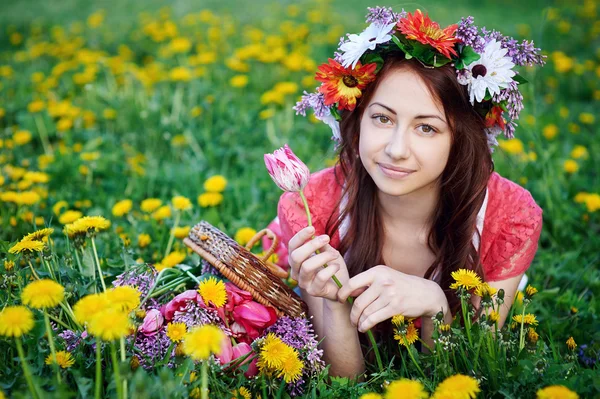 Hermosa mujer en una corona acostada en la hierba en un prado —  Fotos de Stock