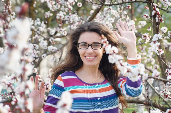 Hermosa joven feliz disfrutando del olor en un jardín de primavera floreciente —  Fotos de Stock