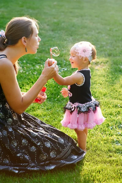 Jeune mère et sa petite fille jouant sur l'herbe — Photo