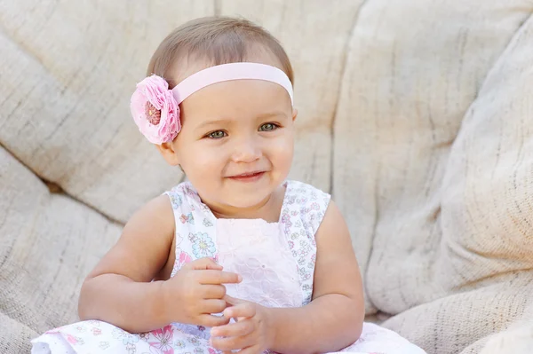 Little baby girl poses on a white chair.  She is smiling happily — Stock Photo, Image