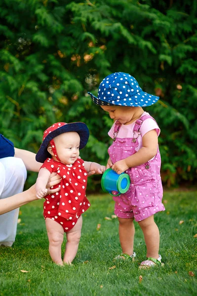 Zwei kleine Mädchen spielen auf dem grünen Gras im Frühlingsgarten — Stockfoto