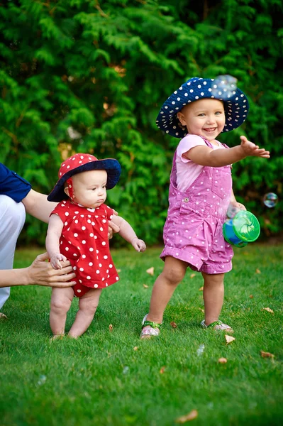 Two little girls playing on the green grass in spring garden — Stock Photo, Image