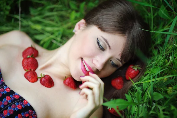 Bela mulher deitada na grama com morangos — Fotografia de Stock