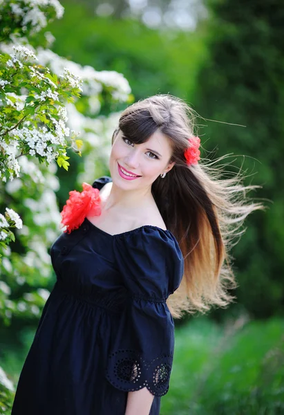 Happy smiling woman walking in blossoming summer park — Stock Photo, Image