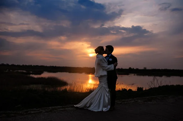 Novia y novio besándose al atardecer hermosa pareja romántica casada —  Fotos de Stock