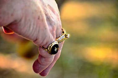 Alyansla sarkık bir son sınıf öğrencisinin eli siyah bir akik yüzüğünün yakın çekimi.