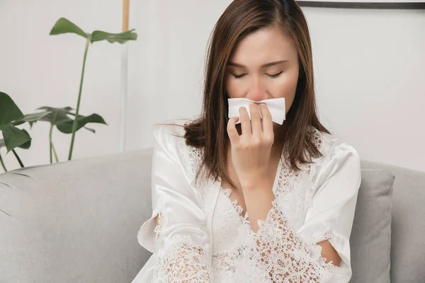 女性のアレルギー性鼻炎の症状 風邪をひいた白夜の服を着た病気の女性が家のティッシュペーパーに彼女の鼻を吹いている 寒い天候アレルギー — ストック写真