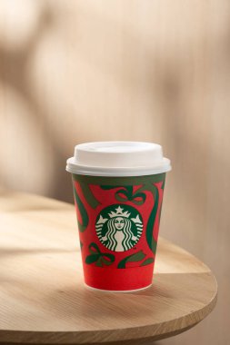 Starbucks 'ın sıcak kahvesi ahşap bir masada sunuluyor, kaliteli lezzet, sıcak atmosfer ve ikonik kahve alma tarzı sunuluyor..