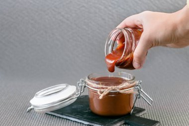 Tuzlu karamel kavanozda gri bir arka planda, bir taş standında. Yan görünüm.